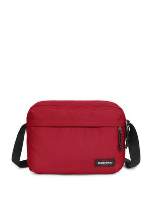 Borsa a tracolla rossa in nylon con forma rettangolare piatta, strap regolabile nera e chiusura con zip. Presenta una patch con il logo sulla parte anteriore.