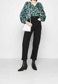 Kwiatowa, długorękawowa bluzka w ciemnoniebieskim kolorze, z zielonymi i białymi kwiatami. Połączona z czarnymi spodniami o wysokim stanie i czarnymi botkami. Biała torebka.