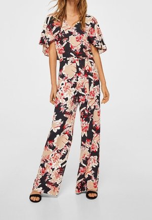 Combinaison florale avec un décolleté en V, des manches larges et une taille cintrée. Présente un fond noir avec des motifs floraux rouge et beige.