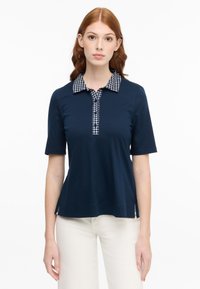 Navy-Poloshirt mit karierter weißer und schwarzer Kragen, kurzen Ärmeln und knöpfbarer Leiste, ausgestattet mit seitlichen Schlitzen am Saum.