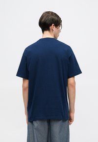 T-shirt in cotone blu navy con maniche corte, vestibilità comoda e scollatura rotonda. La texture appare liscia senza motivi o loghi visibili.