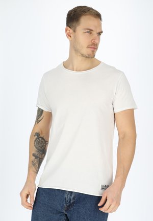 Witte crewneck t-shirt van katoen, met korte mouwen, voorzien van een klein merklabel rechtsonder, gedragen met blauwe spijkerbroek.