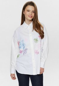 Cămașă albă cu butoni, decorată cu broderie florală colorată în nuanțe de roz, albastru, verde și mov. Material din bumbac moale, cu mâneci lungi.