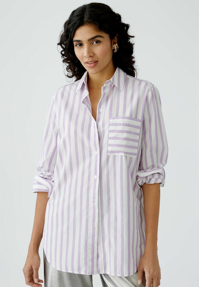 Striped button-up shirt in light purple and white, featuring a single chest pocket and rolled sleeves. Soft fabric with a relaxed fit.