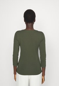 Dlouhý rukáv, olivově zelený top z měkké tkaniny s kulatým výstřihem a zakřiveným lemem, s přiléhavými rukávy a hladkým povrchem.