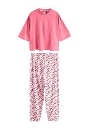 Roze top met korte mouwen gecombineerd met een witte broek met een patroon van kleine verspreide roze en rode hartjes.