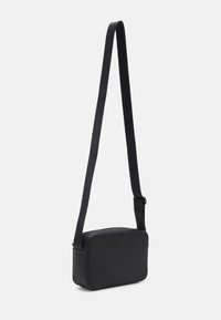 Czarna torba na ramię o prostokątnym kształcie, gładkiej teksturze, regulowanym pasku i zamknięciu na zamek. Minimalistyczny design, brak widocznych wzorów lub akcentów.