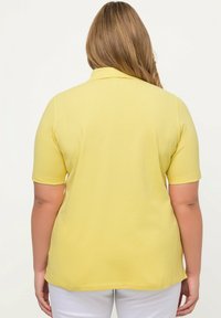 Koszulka polo z krótkim rękawem w jaskrawym żółtym kolorze, wykonana z miękkiego materiału. Posiada klasyczny kołnierzyk i luźny krój, z gładką fakturą.