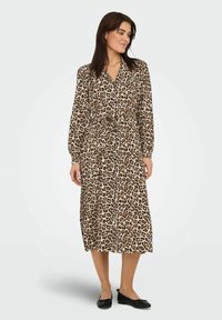 Leopardmönstrad midi-klänning med långa ärmar, bälte i midjan och kavajkrage. Tillverkad av mjukt material, med en beige och brun färgskala.