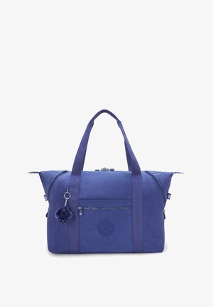 Sac de sport en tissu violet avec poignées supérieures doubles, poche zippée à l'avant et patch logo rond, agrémenté d'un porte-clé pompon.