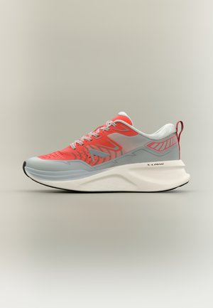 Vaaleanharmaa ja kirkkaan korallinen urheilukenkä paksulla valkoisella pohjalla, kuvioidulla päällisellä, valkoisilla nauhoilla ja punaisella kantalenkillä neutraalilla taustalla.