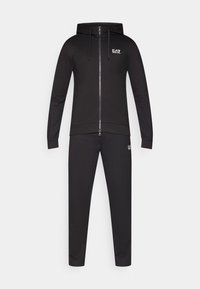 Μαύρη φόρμα με φερμουάρ και κουκούλα, καθώς και ταιριαστό παντελόνι. Κατασκευασμένη από απαλό ύφασμα, διαθέτει λεπτομέρειες με το λογότυπο EA7 και στα δύο κομμάτια.