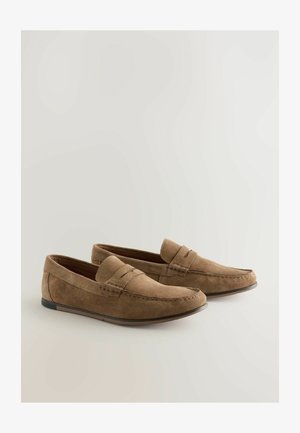 Mocassini in suede marrone con punta arrotondata, cuciture decorative e suola in gomma bassa, caratterizzati da un accento orizzontale sulla pattina.