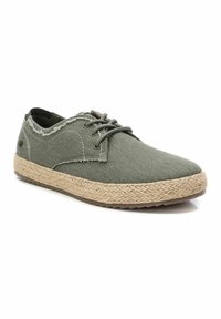 Zapatos de tela gris con suela de yute trenzada. Cuentan con una punta redondeada, bordes deshilachados y cordones planos. La superficie texturizada añade detalle.