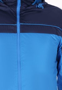 Chaqueta con capucha azul y navy que presenta un cierre de cremallera, textura suave y un diseño de paneles horizontales en contraste.