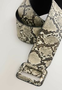 Large ceinture en fausse peau de serpent avec un motif crème, noir et marron. Dotée d'une boucle rectangulaire et d'une texture lisse.