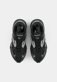 Zapatillas deportivas negras con parte superior de malla y acentos plateados, puntera reforzada y suela texturada. Cierre con cordones y marca en la lengüeta.