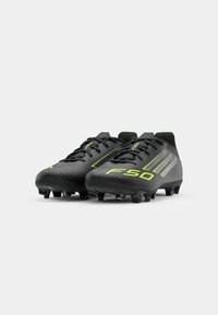 Black football boots with textured surface, neon green accents, lace-up design, and conical cleats for traction on grass surfaces.