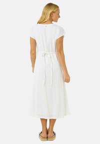 Robe blanche, longueur genou, confectionnée en tissu léger. Elle présente un détail de lien à l'arrière et des manches courtes. Texture lisse avec un design minimaliste.