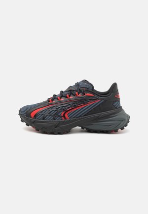 Zapatilla deportiva negra y roja con malla transpirable, suela texturizada para tracción y talón acolchado sobre un fondo blanco.