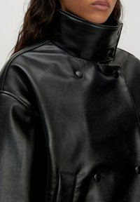Schwarze Lederjacke mit hohem Kragen, doppelt gelegtem Design, zwei auffälligen Knöpfen und glatter Textur.