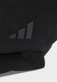 Black fabric bag featuring a textured surface and a raised black logo with three triangular shapes, positioned diagonally.