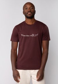 Bordeauxrotes Baumwoll-T-Shirt mit kurzen Ärmeln und Rundhalsausschnitt, das weißen Text mit der Aufschrift "fass das nicht an!" über der Brust trägt.