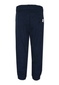 Tummansinisiä housuja, joissa on joustava vyötärö ja joustavat hihnat, valmistettu pehmeästä kankaasta, takatasku ja napin yksityiskohta.