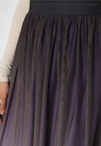 La gonna trasparente presenta un design a strati di colore viola scuro, che sfuma nel nero alla base, con una vita strutturata per una vestibilità sicura.