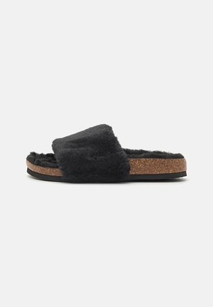 Sorte sandaler med pelspynt, bred stropp, kork-mellomsåle og teksturert gummisåle. Myk overflate for komfort.