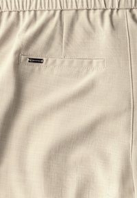 Beiga shorts i lättviktsmaterial med en subtil textur, med elastisk midja och en enda bakficka med en metalldetalj.