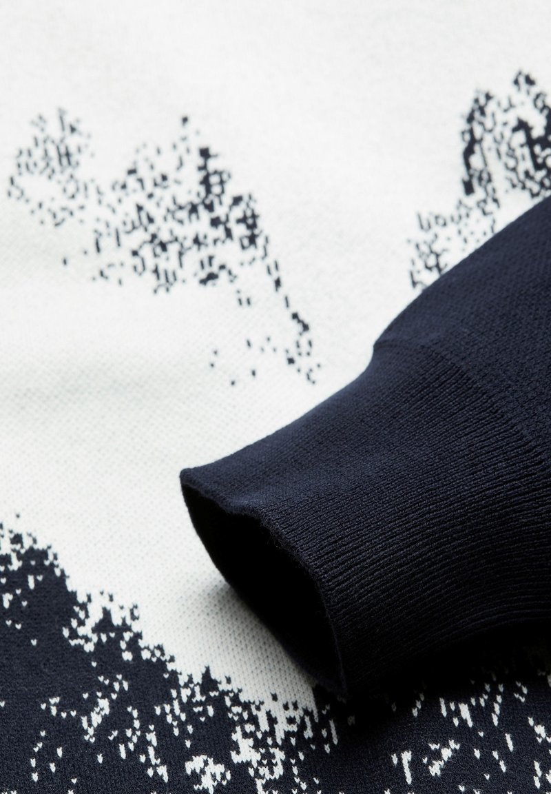 Marineblauer Strickpullover mit einem strukturierten Muster, das ein weiß-schwarzes, pixeliertes Design aufweist. Der Bund ist gerippt und sorgt für einen engen Sitz.