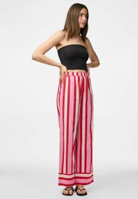 Pantalons larges rayés en tissu rose et rouge avec une coupe décontractée, dotés d'une taille à cordon et d'une texture lisse et légère.
