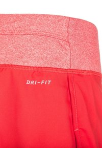 Pantalones cortos rojos Dri-FIT con una cintura texturizada, que presentan un acabado de tela suave y un logo blanco en el lado inferior izquierdo.