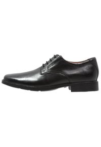 Chaussure habillée en cuir noir avec un bout arrondi, texture lisse, six œillets pour les lacets et une semelle en caoutchouc basse.