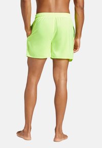 Pantaloncini da bagno verde neon con vita elastica e tasche laterali, realizzati in tessuto leggero. Presentano una vestibilità comoda e una texture liscia.