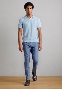 Φορώντας πουλόβερ πλεκτό polo σε ανοιχτό γαλάζιο με σχέδιο καλώδιο, συνδυασμένο με ανοιχτό γαλάζιο παντελόνι στενής γραμμής και καφέ παπούτσια slip-on. Λεία υφή, κοντά μανίκια.