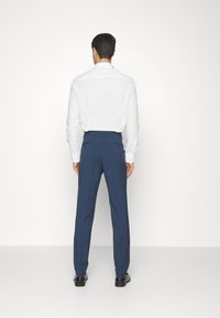 Blue dress pants with a tailored fit, flat front, and double back pockets, paired with a white button-up shirt and black shoes.