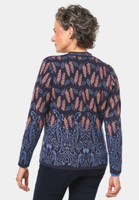 Gilet en tricot bleu marine avec des motifs de feuilles et géométriques contrastants en orange et bleu, doté de manches longues et d'un col rond.