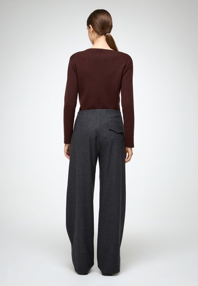 Pruunist kudumist särk, millel on ruudukujuline kaelus, koos laia jala tumashallide pükstega, millel on tagatasku ja viimistletud lõige.