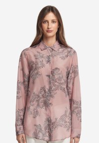 Rosa långärmad blus i genomskinligt tyg med blommiga och paisleymönster i silver. Har en klassisk krage och knappstängning framtill.