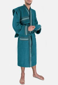 Türkisfarbener Frottee-Bademantel mit einem Schalkragen, Fronttaschen und horizontalen Streifenakzenten in dunkleren Tönen. Gürtel in der Taille, knielang.