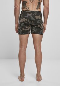 Boxer shorts en imprimé camouflage avec une ceinture élastique, présentant des nuances de vert foncé, de marron et de gris clair. Fabriqués dans un matériau doux.