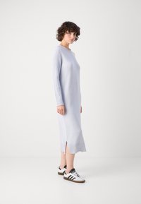 Lyseblå strikket kjole med lange ribbestrikkede ermer og sideslisse, kombinert med hvite og svarte sneakers med tre striper.