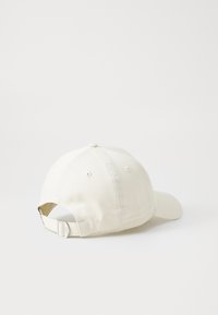 Bílá bavlněná baseballová čepice s klenutým špicem, nastavovatelným páskem na zadní straně a šitými detaily. Minimalistický design bez loga.