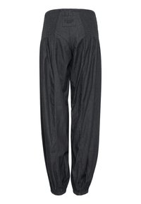 Pantalon noir ample avec taille élastiquée froncée et poignets élastiques froncés, vu de dos sur fond blanc uni.