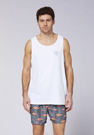 White sleeveless tank top with a small graphic logo on the chest, paired with grey swim shorts featuring an orange kangaroo pattern.