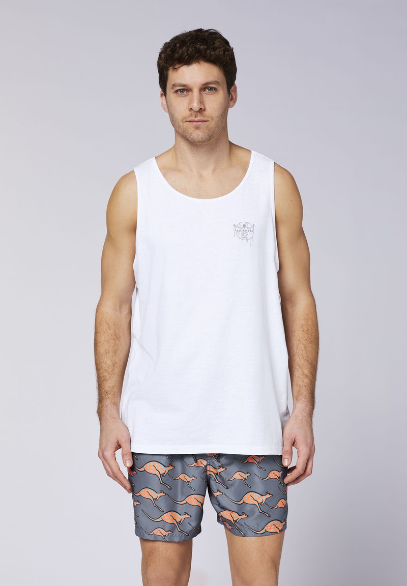Weißes ärmelloses Tanktop mit einem kleinen grafischen Logo auf der Brust, kombiniert mit grauen Badeshorts mit einem orangen Kanguru-Muster.