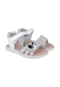 Sandalias infantiles blancas y plateadas con un acento plateado en forma de corazón, que presentan un acabado en cuero suave, correas ajustables y una suela texturizada.