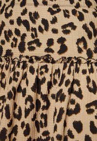 Luipaardprint stof met een textuur van beige achtergrond, met zwarte en bruine vlekken. Rimpelranddetail voegt dimensie toe aan het ontwerp.